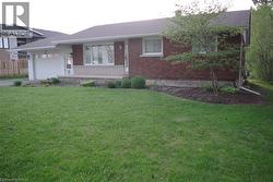 Single story home with brick siding, a front yard, a garage, a chimney, and a shingled roof -