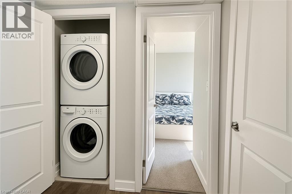 Laundry area featuring stacked washer / drying machine and dark wood finished floors - 185 Windale Crescent Unit# 5A, Kitchener, ON - Indoor Photo Showing Laundry Room