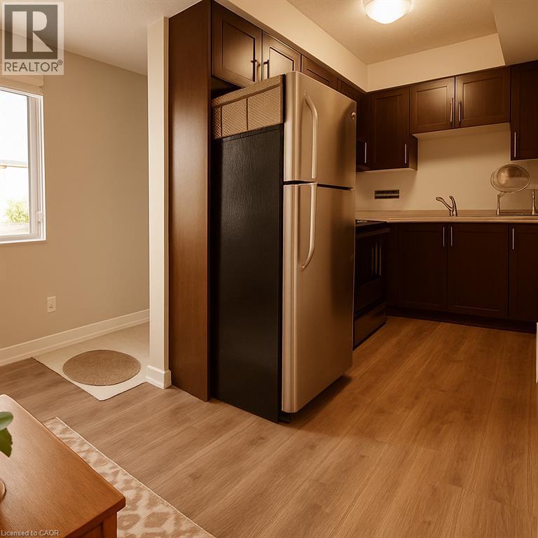 Kitchen featuring freestanding refrigerator, dark brown cabinetry, light countertops, light wood-style flooring, and black stove - 185 Windale Crescent Unit# 5A, Kitchener, ON - Indoor Photo Showing Kitchen