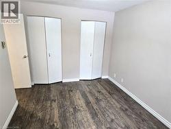 Unfurnished bedroom featuring multiple closets and dark wood-style floors -