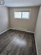 Empty room featuring a baseboard heating unit and dark wood-style floors -