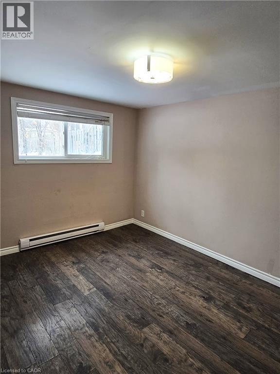 Unfurnished room featuring baseboard heating and dark wood finished floors - 50 Scenic Drive Unit# Lower, Kitchener, ON - Indoor Photo Showing Other Room