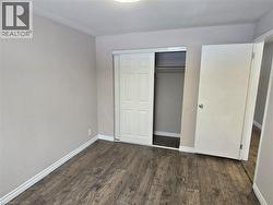 Unfurnished bedroom with dark wood-style floors and a closet -