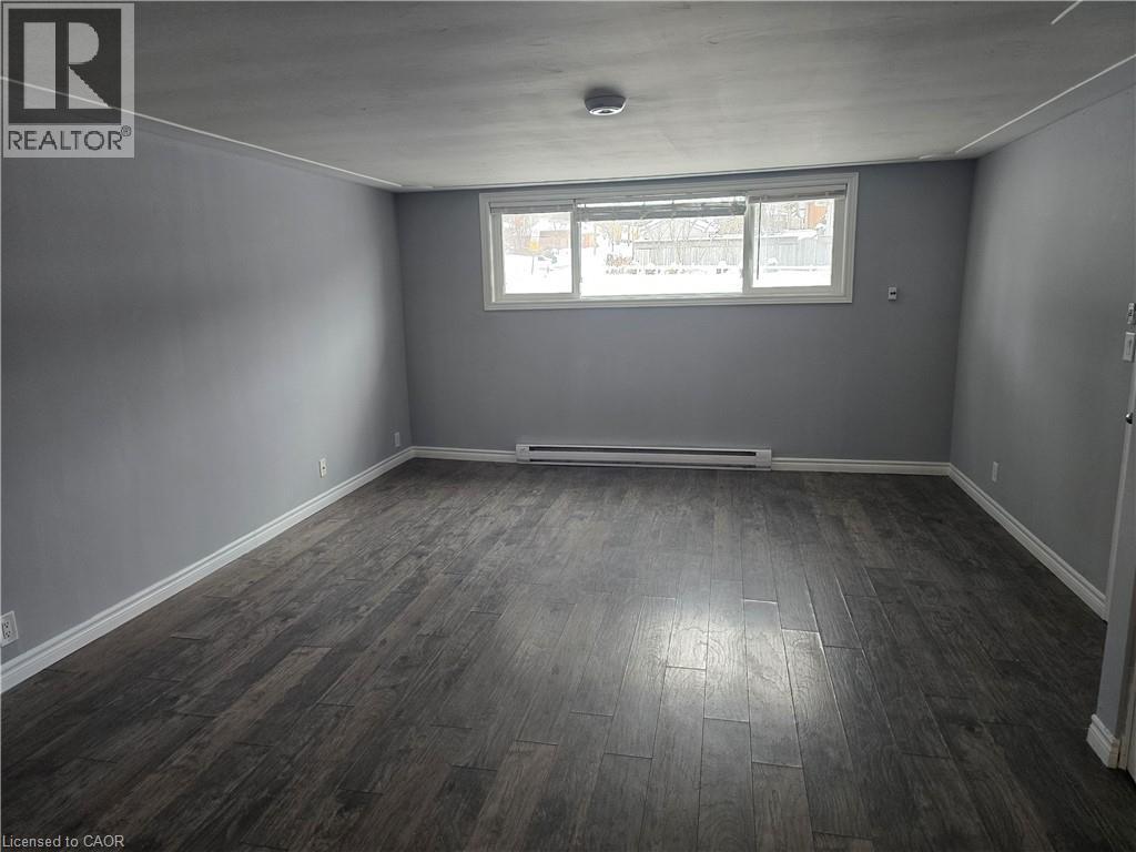 Empty room with dark wood finished floors and baseboard heating - 50 Scenic Drive Unit# Lower, Kitchener, ON - Indoor Photo Showing Other Room