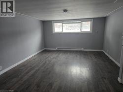 Empty room with dark wood finished floors and baseboard heating -