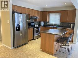 Kitchen with stainless steel appliances, brown cabinets, a kitchen bar, dark countertops, and a textured ceiling -