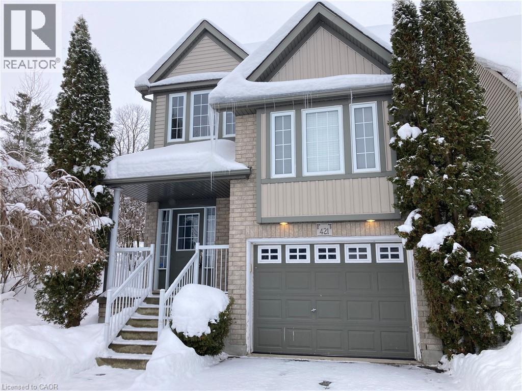 View of front of property featuring an attached garage, covered porch, board and batten siding, and brick siding - 421 White Birch Avenue, Waterloo, ON - Outdoor With Facade