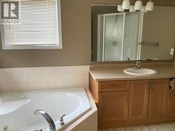 Bathroom featuring a whirlpool tub, vanity, and a stall shower -