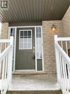 Doorway to property featuring brick siding and covered porch -