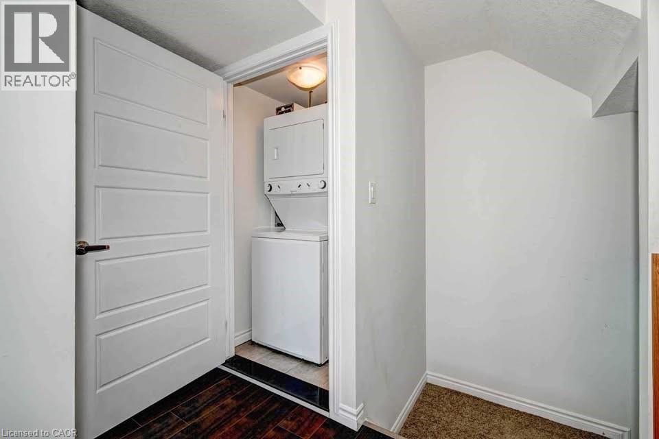 Laundry room with stacked washer / dryer, dark wood-style floors, a textured ceiling, and vaulted ceiling - 1430 Highland Road W Unit# 7C, Kitchener, ON - Indoor Photo Showing Laundry Room