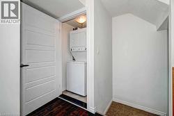 Laundry room with stacked washer / dryer, dark wood-style floors, a textured ceiling, and vaulted ceiling -