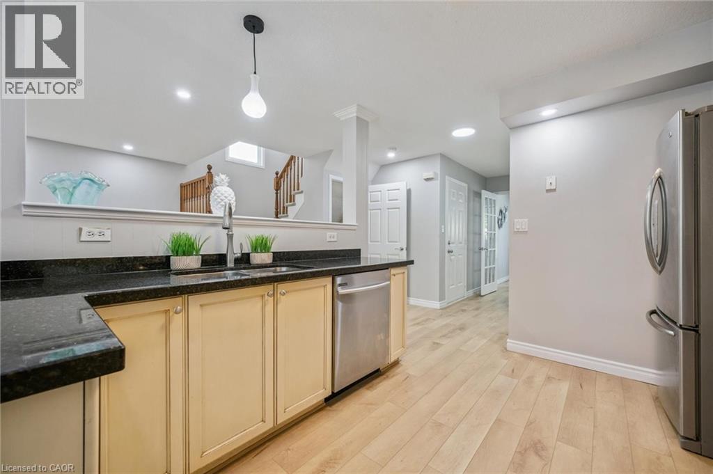 Kitchen with appliances with stainless steel finishes, light wood finished floors, dark stone counters, decorative light fixtures, and recessed lighting - 723 Black Cherry Street, Waterloo, ON - Indoor Photo Showing Kitchen With Stainless Steel Kitchen