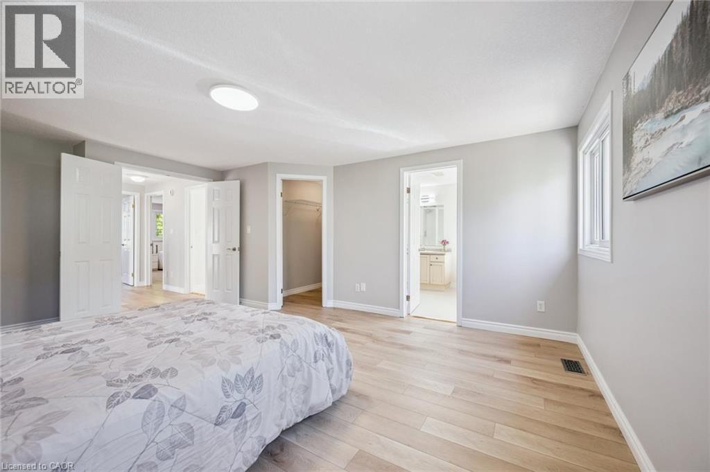 Bedroom featuring a spacious closet, light wood-type flooring, and ensuite bathroom - 723 Black Cherry Street, Waterloo, ON - Indoor Photo Showing Bedroom