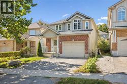 View of front of home with a porch, driveway, an attached garage, roof with shingles, and brick siding -