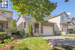 View of front of home featuring asphalt driveway, covered porch, a garage, and brick siding -