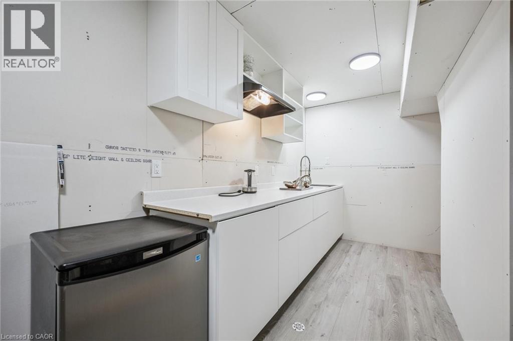 Kitchen with open shelves, light countertops, white cabinetry, light wood-type flooring, and stainless steel dishwasher - 723 Black Cherry Street, Waterloo, ON - Indoor Photo Showing Other Room