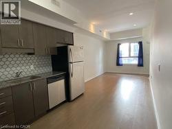 Kitchen featuring stainless steel appliances, light wood finished floors, backsplash, gray cabinetry, and light stone counters -