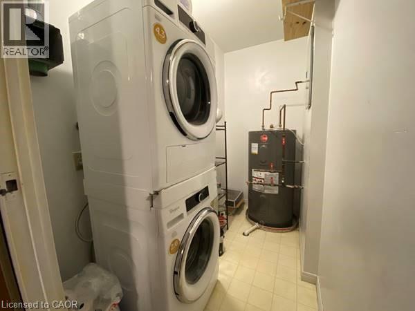 Washroom featuring stacked washer / dryer and water heater - 35 Green Valley Drive Unit# 414, Kitchener, ON - Indoor Photo Showing Laundry Room