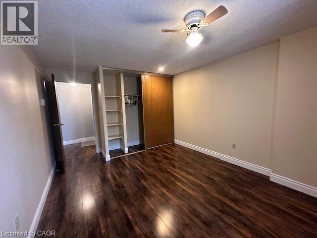 Unfurnished bedroom featuring dark wood-style floors, a textured ceiling, a closet, and ceiling fan - 35 Green Valley Drive Unit# 414, Kitchener, ON - Indoor Photo Showing Other Room