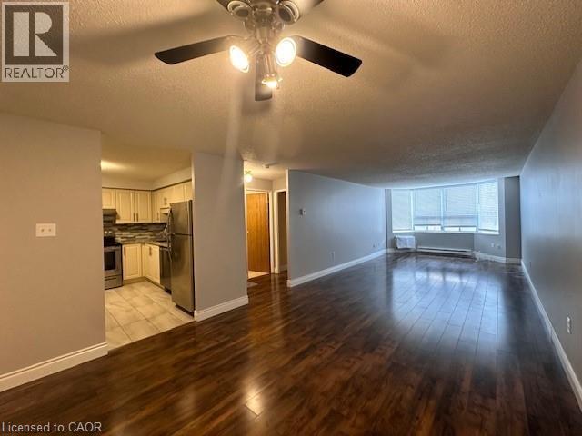 Unfurnished living room with a textured ceiling, light wood finished floors, ceiling fan, and a baseboard radiator - 35 Green Valley Drive Unit# 414, Kitchener, ON - Indoor