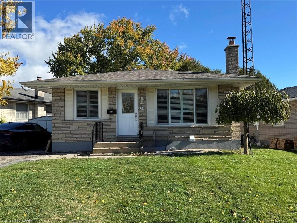 View of front of house featuring stone siding, a chimney, a front yard, and roof with shingles - 86 Hillsborough Crescent Unit# Main, Kitchener, ON - Outdoor With Facade