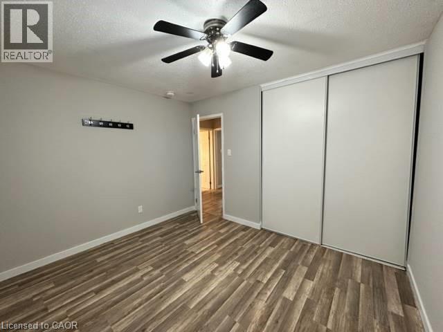 Unfurnished bedroom featuring a textured ceiling, dark wood-type flooring, a closet, and ceiling fan - 86 Hillsborough Crescent Unit# Main, Kitchener, ON - Indoor Photo Showing Other Room