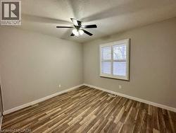 Unfurnished room with a textured ceiling, dark wood-type flooring, and ceiling fan -