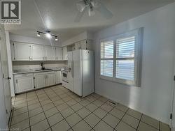 Kitchen featuring white appliances, light countertops, white cabinets, a textured ceiling, and decorative backsplash -