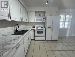 Kitchen with white appliances, white cabinetry, and open shelves -