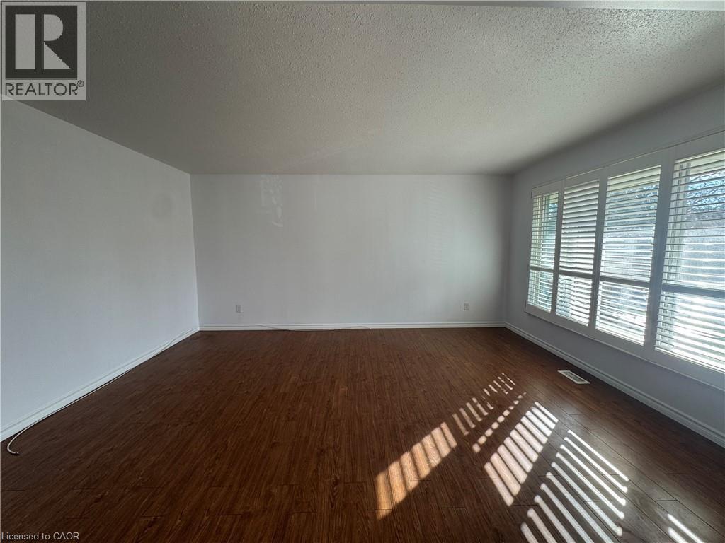 Unfurnished room featuring a textured ceiling and dark wood finished floors - 86 Hillsborough Crescent Unit# Main, Kitchener, ON - Indoor Photo Showing Other Room