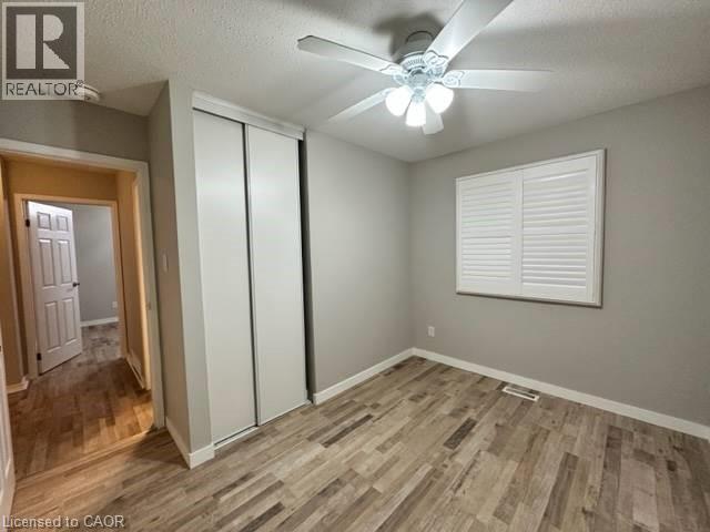 Unfurnished bedroom featuring a textured ceiling, light wood-type flooring, a closet, and ceiling fan - 86 Hillsborough Crescent Unit# Main, Kitchener, ON - Indoor Photo Showing Other Room