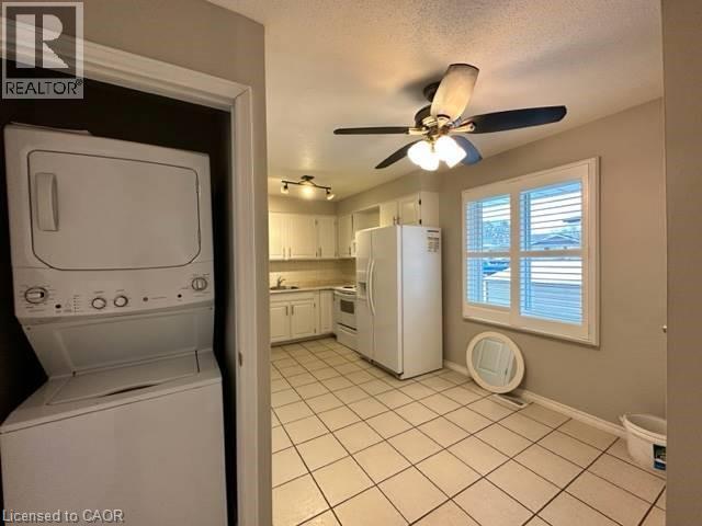 Laundry room featuring stacked washing machine and dryer, light tile patterned floors, and a ceiling fan - 86 Hillsborough Crescent Unit# Main, Kitchener, ON - Indoor Photo Showing Laundry Room
