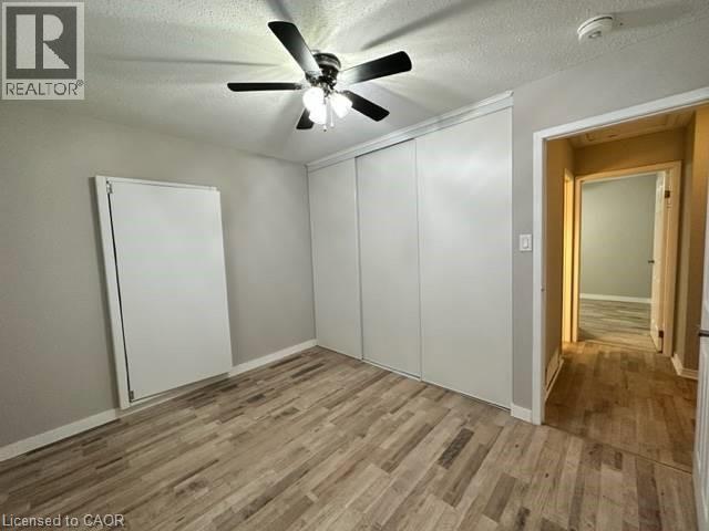 Unfurnished bedroom with a textured ceiling, a closet, ceiling fan, and light wood-style floors - 86 Hillsborough Crescent Unit# Main, Kitchener, ON - Indoor Photo Showing Other Room