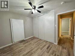 Unfurnished bedroom with a textured ceiling, a closet, ceiling fan, and light wood-style floors -