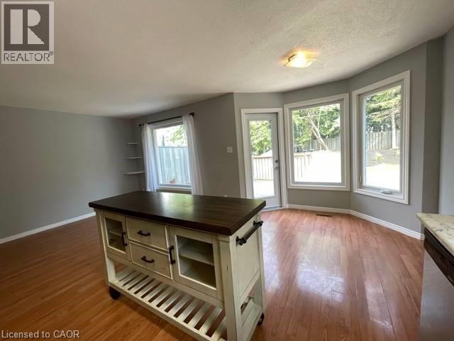 Kitchen with butcher block countertops, light wood-style floors, stainless steel dishwasher, a textured ceiling, and open shelves - 214 Benesfort Crescent, Kitchener, ON - Indoor Photo Showing Other Room