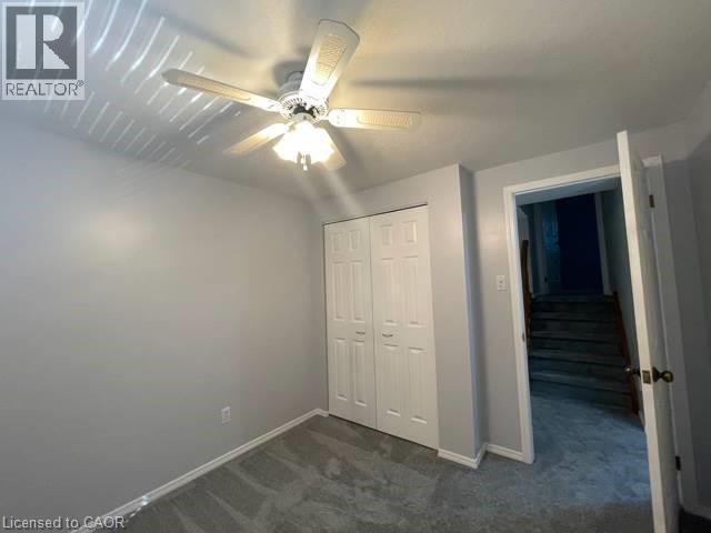 Unfurnished bedroom with dark carpet, a closet, and ceiling fan - 214 Benesfort Crescent, Kitchener, ON - Indoor Photo Showing Other Room