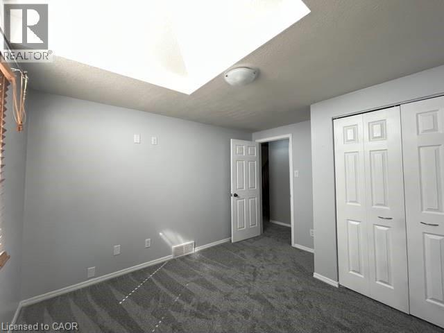 Unfurnished bedroom with dark colored carpet, a closet, and a textured ceiling - 214 Benesfort Crescent, Kitchener, ON - Indoor Photo Showing Other Room