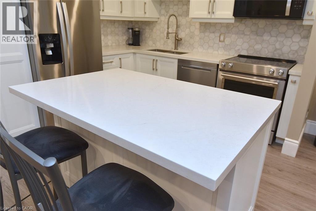 Kitchen with white cabinets, tasteful backsplash, appliances with stainless steel finishes, and light wood-type flooring - 1245 Stephenson Drive Unit# 20, Burlington, ON