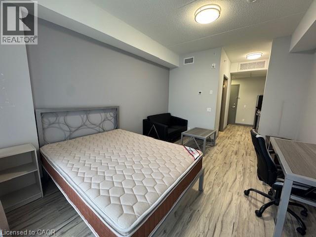Bedroom with an office area, light wood-style flooring, and a textured ceiling - 77 Leland Street Unit# 223, Hamilton, ON - Indoor Photo Showing Bedroom