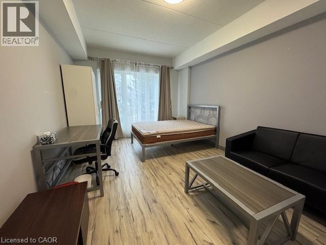 Bedroom with light wood-type flooring, an office area, and a textured ceiling - 77 Leland Street Unit# 223, Hamilton, ON - Indoor Photo Showing Other Room