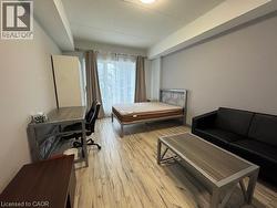 Bedroom with light wood-type flooring, an office area, and a textured ceiling -