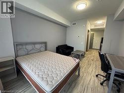 Bedroom with an office area, light wood-style flooring, and a textured ceiling -