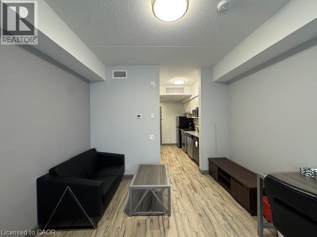 Living room featuring a textured ceiling and light wood-style flooring - 77 Leland Street Unit# 223, Hamilton, ON - Indoor Photo Showing Other Room