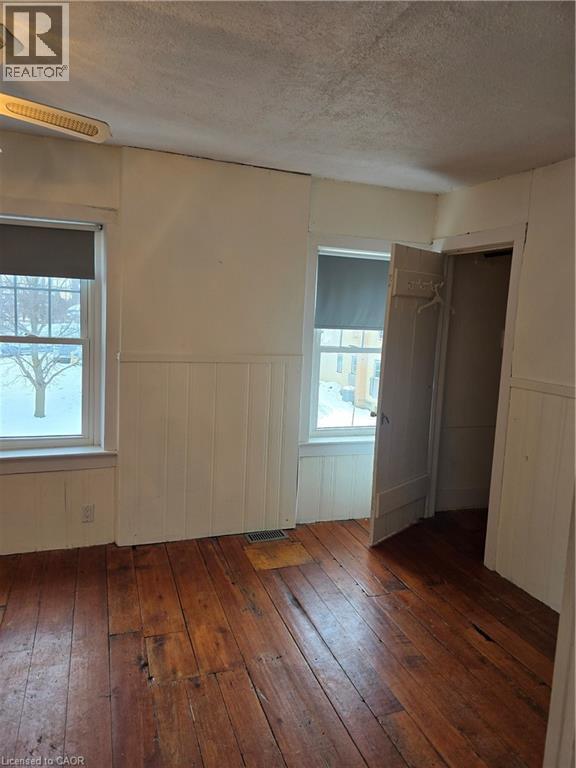 Spare room featuring a wainscoted wall, a textured ceiling, and dark wood-style floors - 10 Centre Street, Elmira, ON - Indoor Photo Showing Other Room
