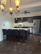 Kitchen featuring refrigerator, a breakfast bar, light countertops, decorative light fixtures, and stainless steel range with electric stovetop -