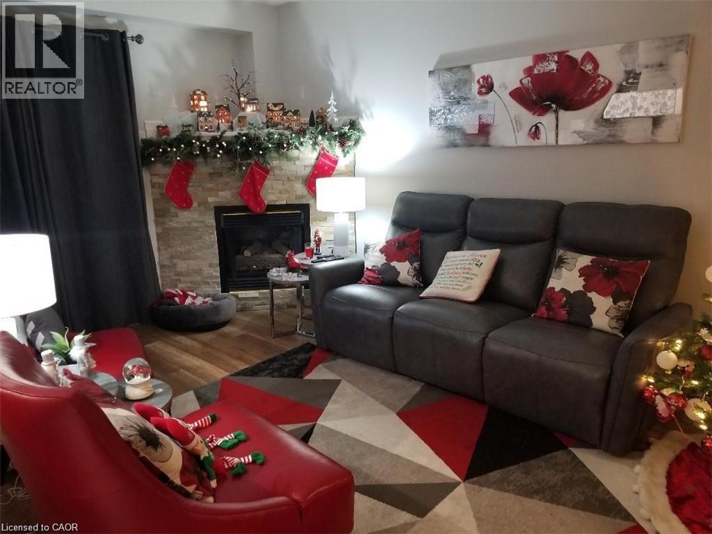 Living room featuring a stone fireplace and wood finished floors - 185 Sulmona Drive, Hamilton, ON - Indoor Photo Showing Living Room With Fireplace