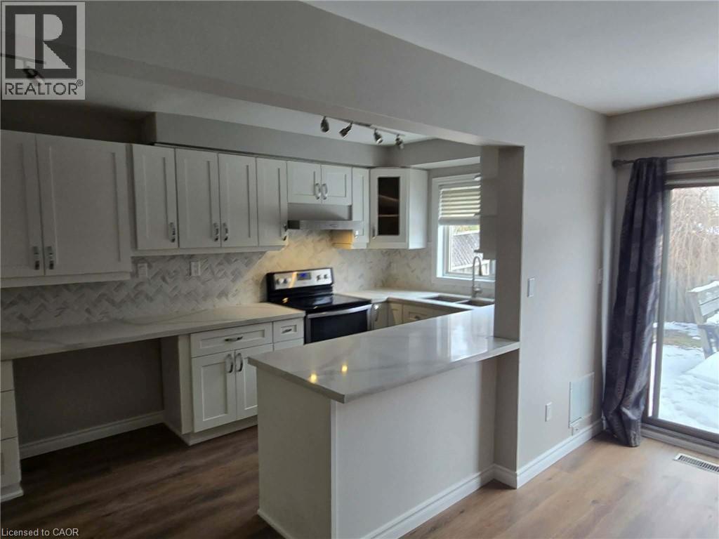 Kitchen featuring stainless steel electric range oven, white cabinetry, rail lighting, and dark wood finished floors - 185 Sulmona Drive, Hamilton, ON - Indoor Photo Showing Kitchen With Double Sink
