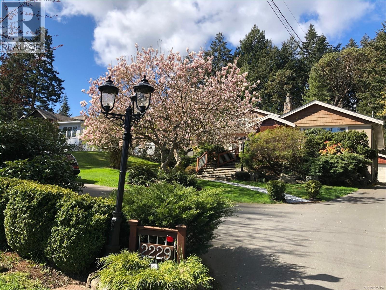 Street level view of main residence with Magnolia tree in summertime bloom - 2229 Arbutus Rd, Saanich, BC - Outdoor