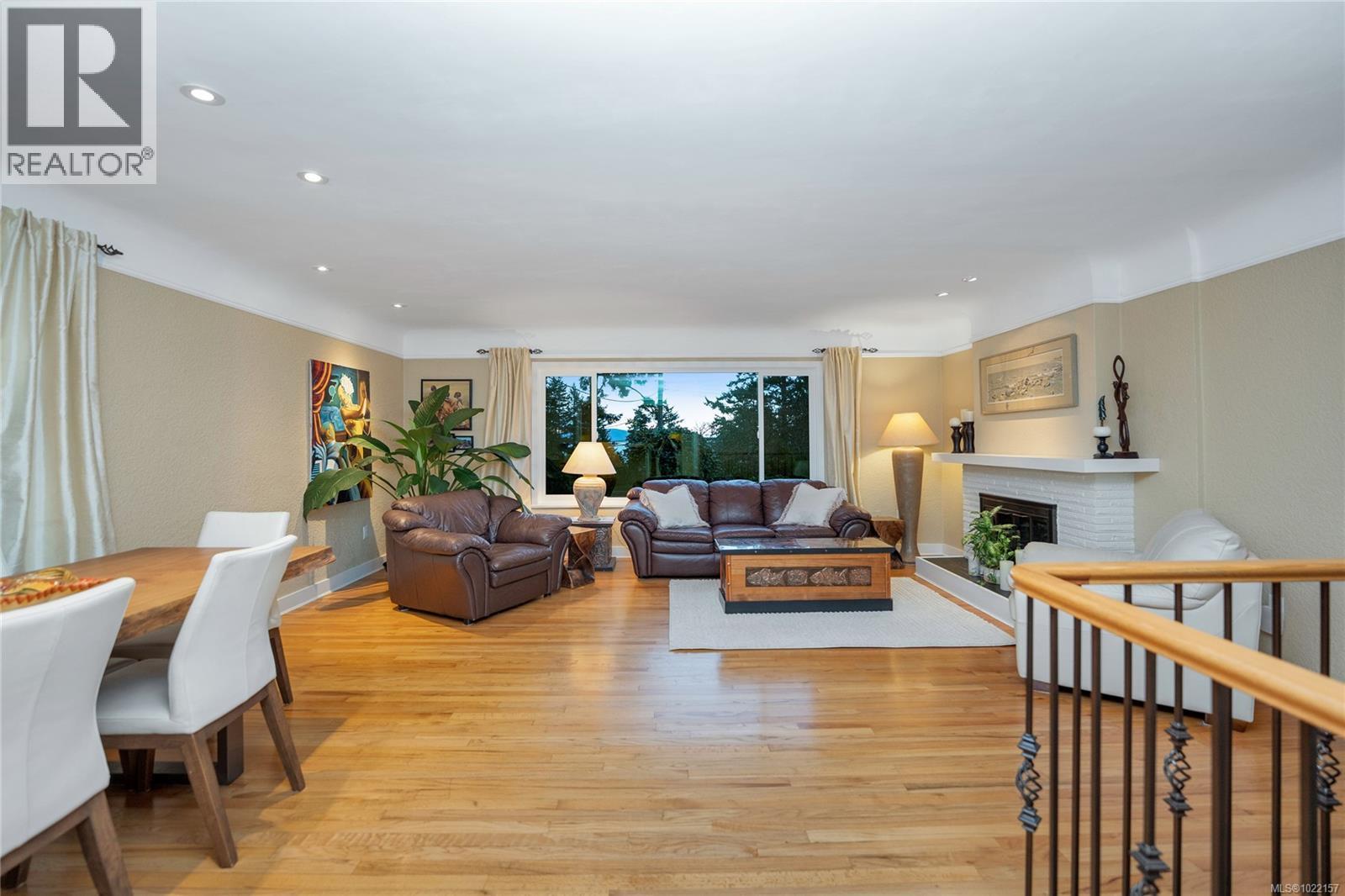 LR includes integrated dining area and water views - 2229 Arbutus Rd, Saanich, BC - Indoor Photo Showing Living Room With Fireplace