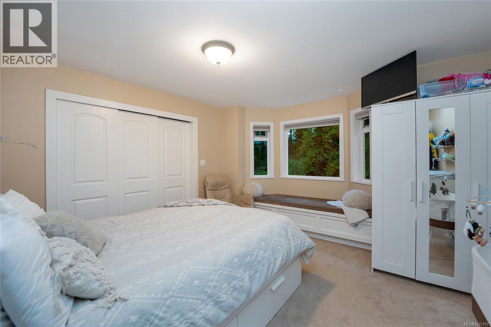 Cottage primary bedroom with window seat overlooking backyard - 2229 Arbutus Rd, Saanich, BC - Indoor Photo Showing Bedroom